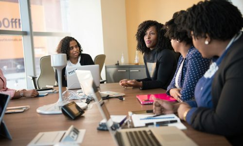 Diverse team of professionals engaging in a collaborative office meeting around a desk.