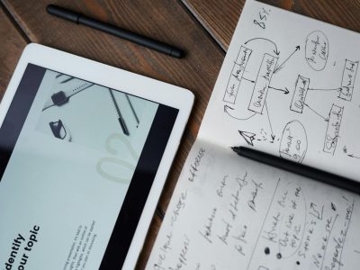 Digital and handwritten brainstorming tools on a wooden desk, ideal for business and study contexts.