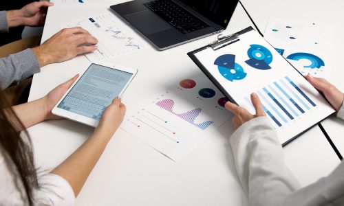 Team analyzing financial charts and digital reports during a business meeting.