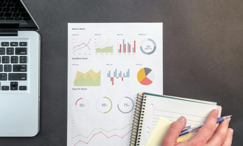 Overhead view of a business desk with charts and a laptop, ideal for data analysis concepts.