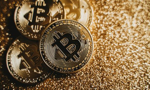 Close-up of Bitcoin cryptocurrency coins on a sparkling gold glitter background, symbolizing digital finance.