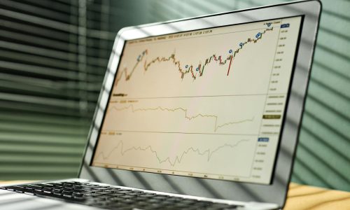 Close-up of a laptop displaying stock market data and graphs in an office setting.