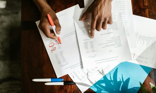 Overhead view of hands highlighting financial documents on a desk.