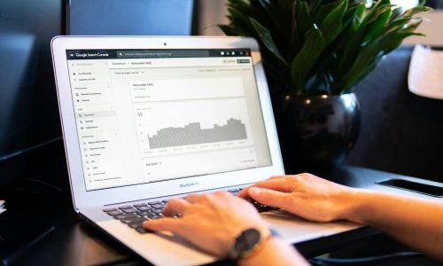 person using macbook air on brown wooden table