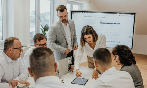 a group of people sitting around a table with laptops